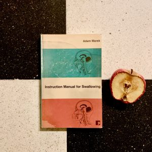 Libro Adam marek sobre fondo damero con manzana podrida